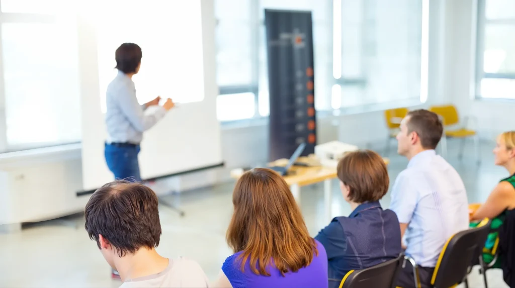 Participants seated in a classroom watching a facilitator present at a whiteboard