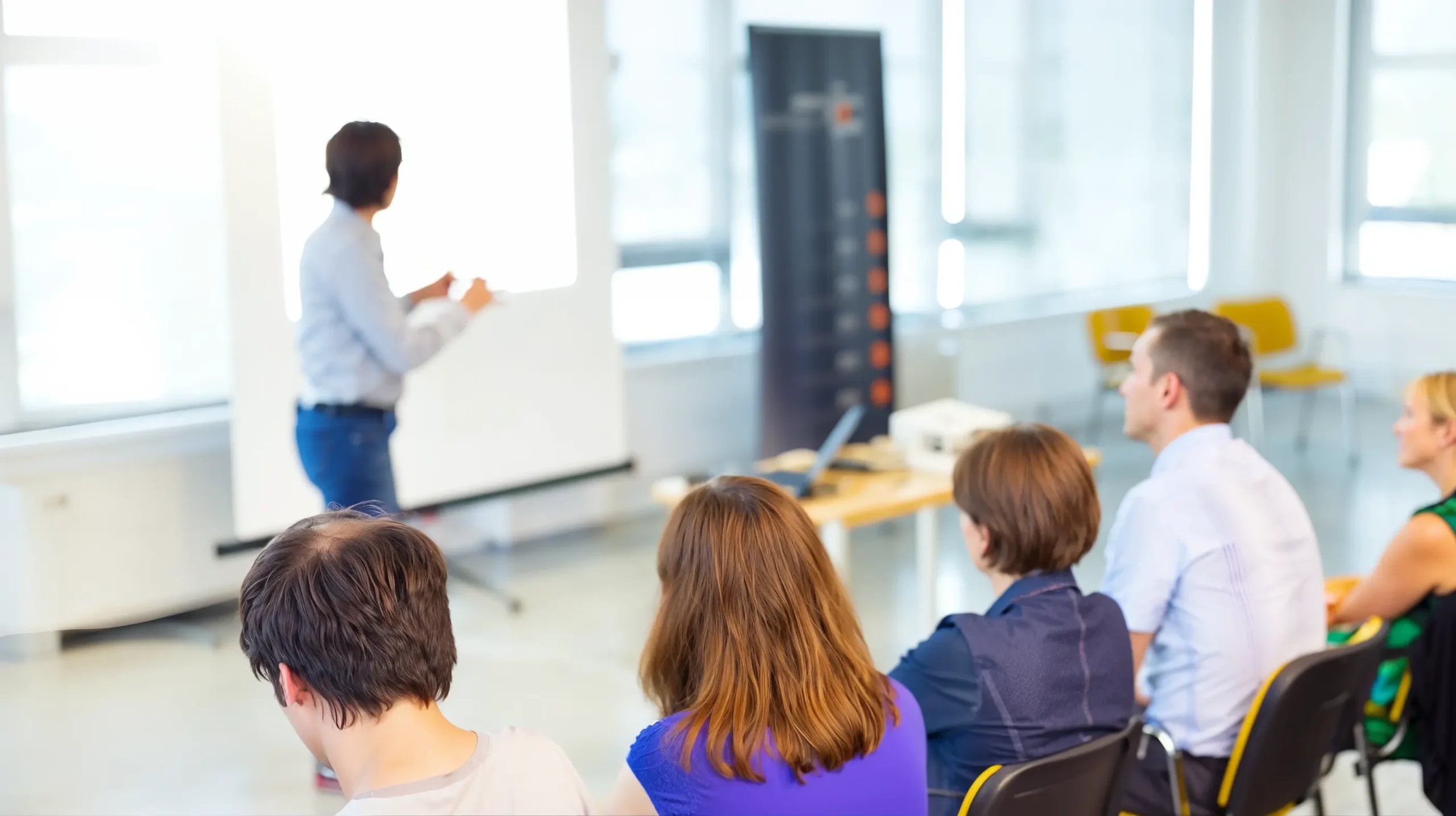 Participants seated in a classroom watching a facilitator present at a whiteboard